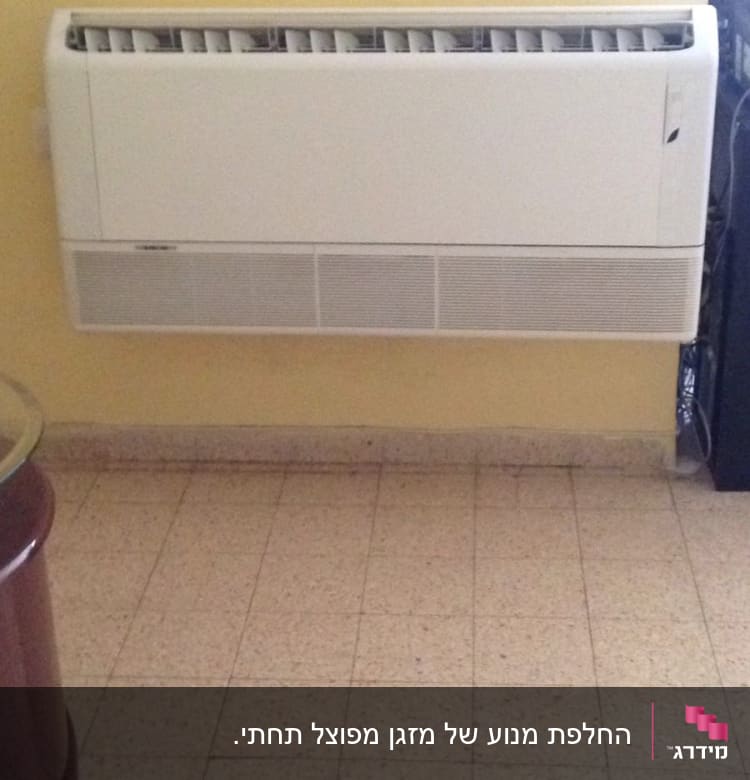 מזגן קיר לבן מותקן על קיר צהוב
